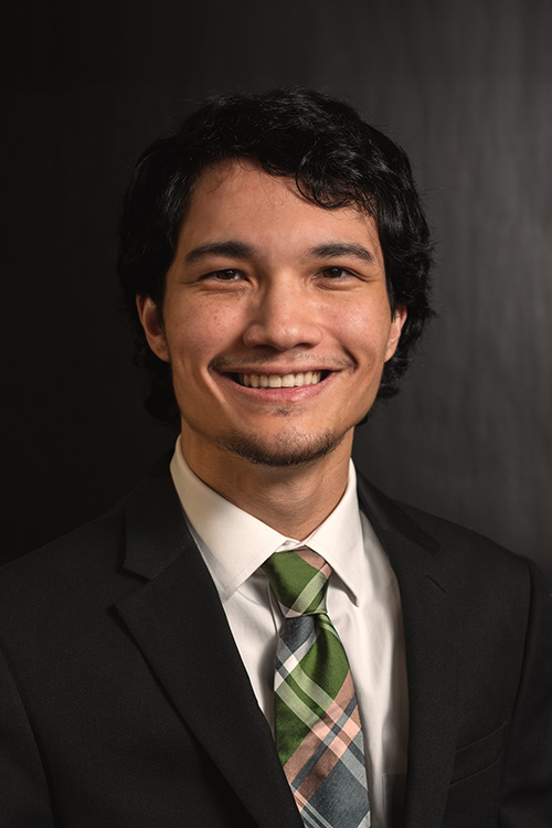 Portrait of a man in a suit and tie, smiling at the camera.